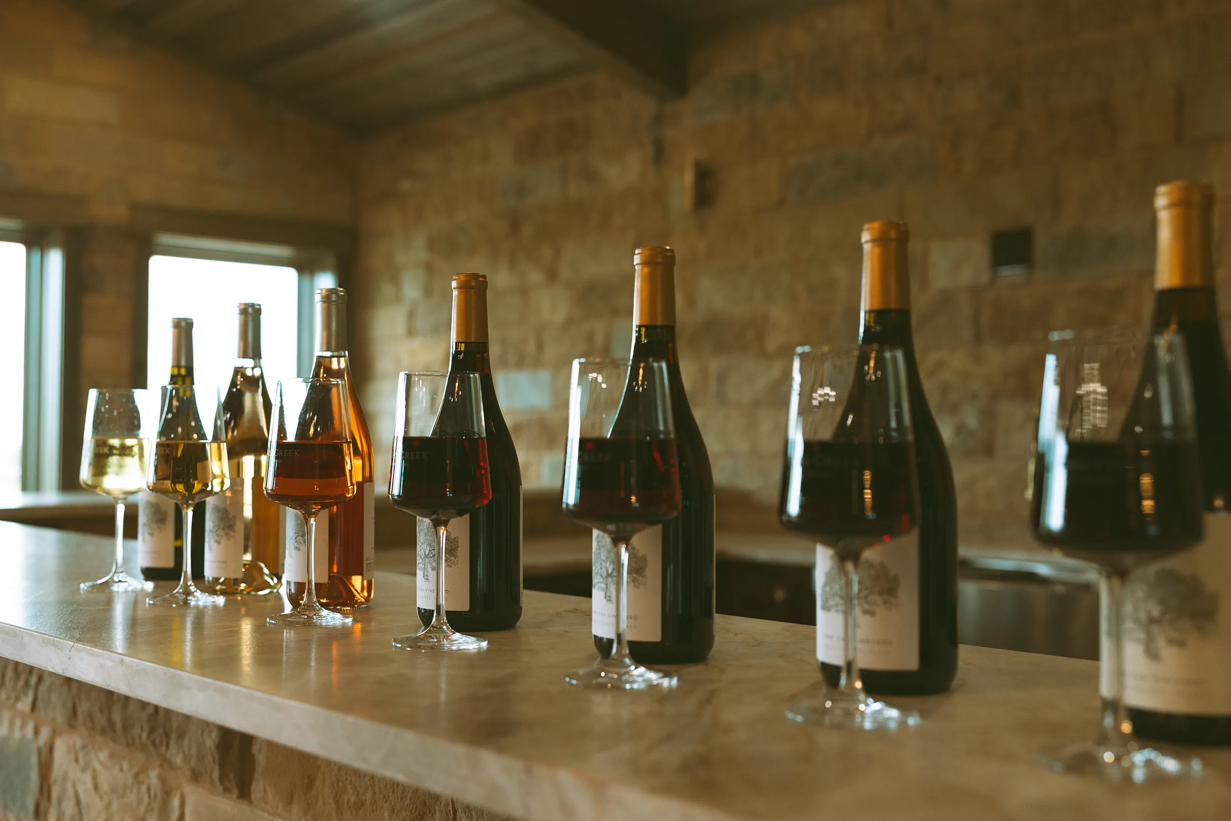Nabors creek wine lined up with wine glasses on a counter.