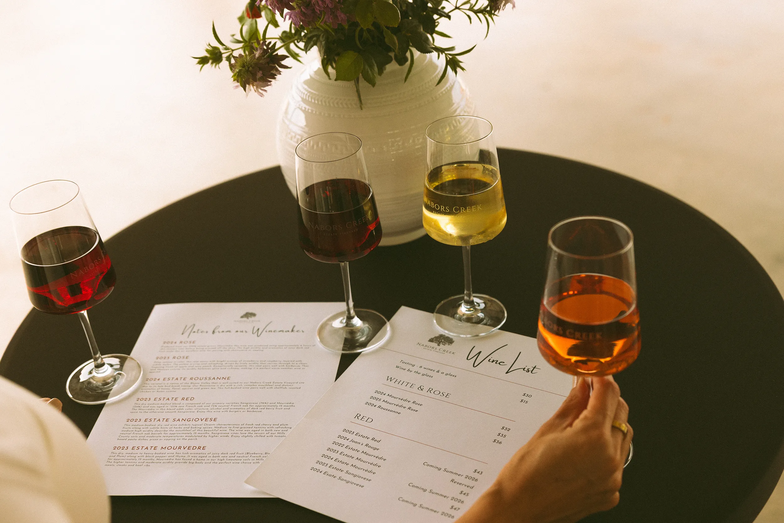 A person sampling wine, whilst reviewing the Nabors Creek wine list.